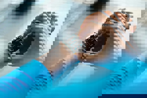 Person interacting with a smartwatch showing time and icons